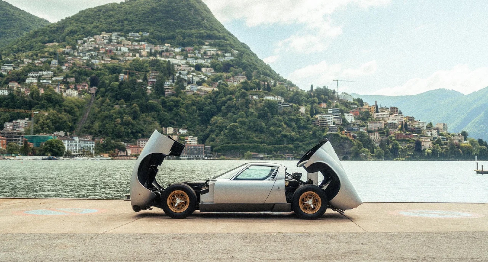 A classic grand-touring car by a lake